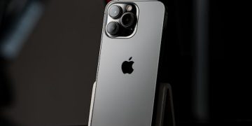 A modern smartphone displayed on a stand against a dark, minimalist background.