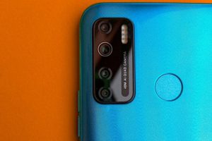 Detailed view of a blue smartphone's camera against an orange background, showcasing modern technology.